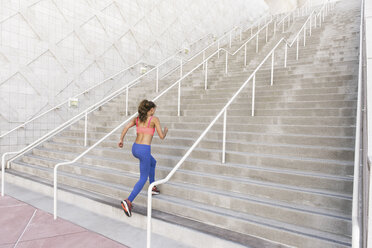 Rear view of young woman wearing sports clothing running up stairs - ISF11448