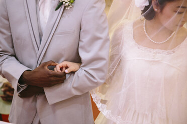 Beschnittene Ansicht der Braut mit Schleier und des Bräutigams, die sich an den Händen halten - ISF11450