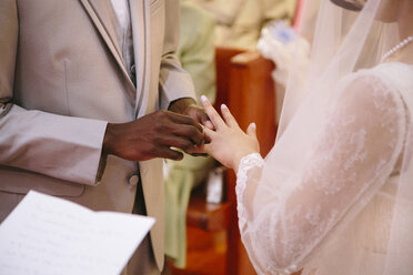 Cropped view of bridegroom putting ring on brides finger at wedding ceremony - ISF11451