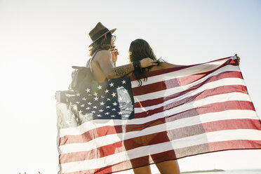 Rückansicht eines jungen Paares, eingewickelt in die amerikanische Flagge, am Newport Beach, Kalifornien, USA - ISF11470