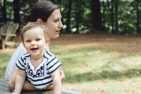 Junge Frau und kleine Tochter auf einer Picknickbank im Wald - ISF11478