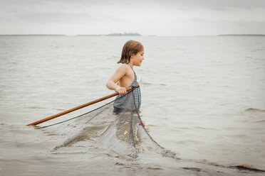 Girl learning how to use traditional fishing net, Sanibel Island, Pine Island Sound, Florida, USA - ISF11485
