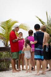 Kinder um einen Lehrer mit einer Kokosnuss, Sanibel Island, Pine Island Sound, Florida, USA - ISF11487