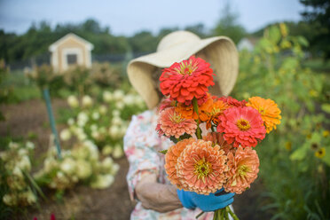 Ältere Frau mit Blumen vor dem Gesicht auf einem Bauernhof - ISF11503