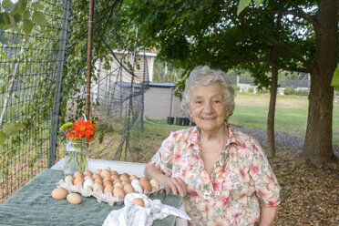 Ältere Frau posiert neben einem Tablett mit Eiern auf dem Bauernhof - ISF11511