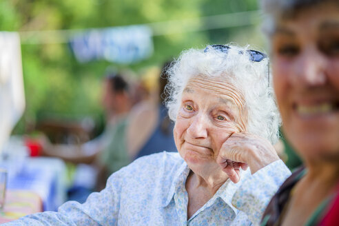 Ältere Frau träumt beim Tomatenessen von einem Festival - ISF11520