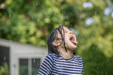 Junges Mädchen im Garten, das fallendes Wasser mit dem Mund auffängt - ISF11521