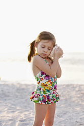 Porträt eines Mädchens, das einer Muschel am Strand zuhört, Sanibel, Florida, USA - ISF11523