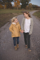 Two young girls walking along country road, hand in hand - ISF11551