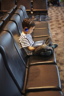 Junge sitzt im Wartebereich eines Flughafens und benutzt ein digitales Tablet - ISF11558