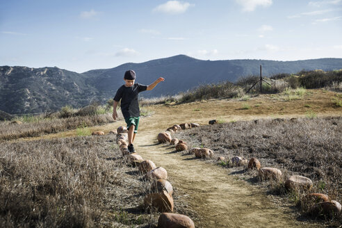 Boy stepping across row of footpath stones, Thousand Oaks, California USA - ISF11568