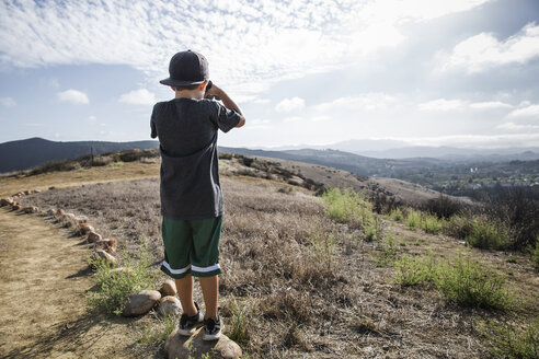 Rear view of boy looking through binoculars from footpath stone, Thousand Oaks, California USA - ISF11569