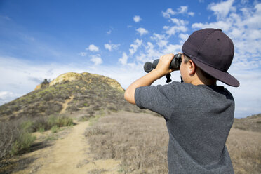 Boy looking through binoculars at landscape, Thousand Oaks, California USA - ISF11570