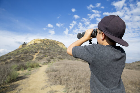 Boy looking through binoculars at landscape, Thousand Oaks, California USA - ISF11570