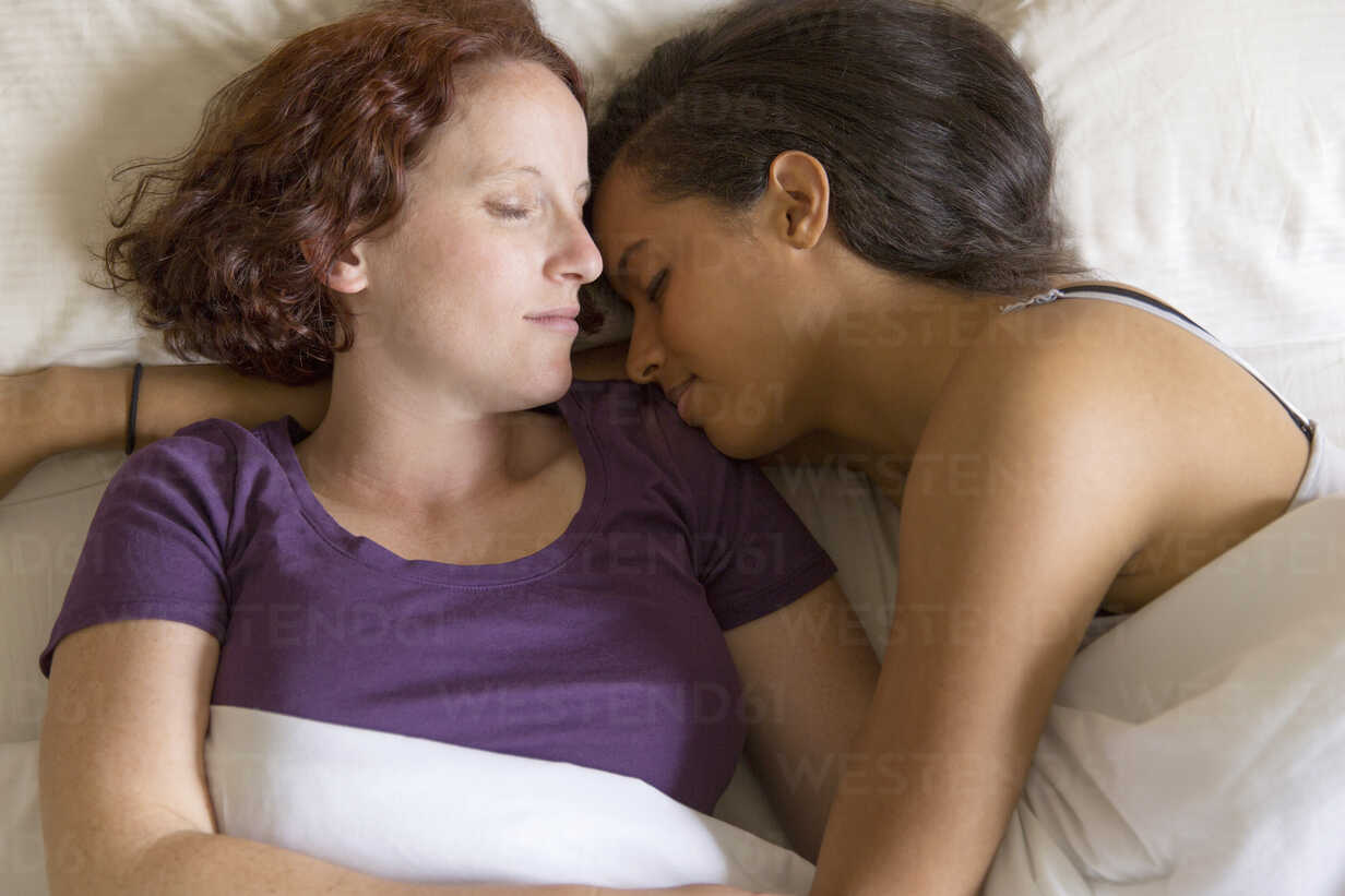 High angle view of lesbian couple lying in bed hugging, sleeping stock photo