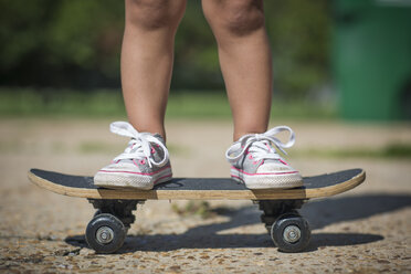 Beine eines Mädchens mit Segeltuchschuhen, das auf einem Skateboard steht - ISF11604