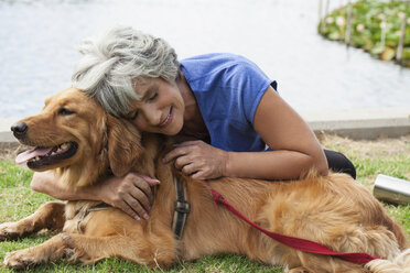 Mature woman hugging dog, outdoors - ISF11610