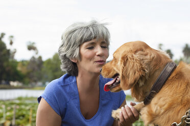 Mature woman petting dog, outdoors - ISF11611