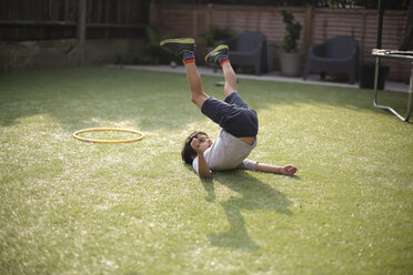 Boy in garden lying on grass, legs raised - ISF11684