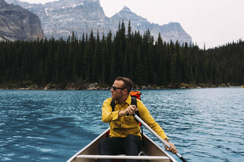 Vorderansicht eines erwachsenen Mannes, der mit einem Kanu paddelt, Blick in die Ferne, Moraine Lake, Banff National Park, Alberta Canada - ISF11688