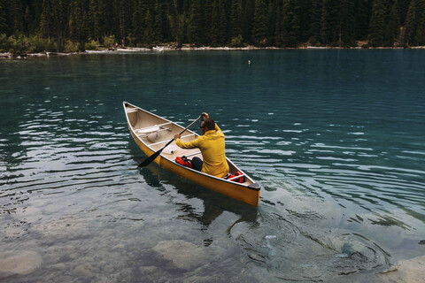 Hochformatige Rückansicht eines erwachsenen Mannes beim Paddeln auf dem Moraine Lake, Banff National Park, Alberta Kanada, lizenzfreies Stockfoto
