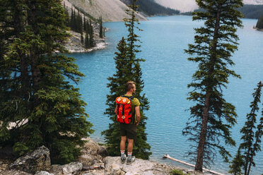 Rückansicht eines mittelgroßen erwachsenen Mannes, der am Rande einer Klippe steht und auf den Moraine-See blickt, Banff National Park, Alberta Kanada - ISF11701