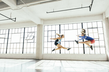 Low angle side view of young women in gym doing mid air lunge - ISF11715