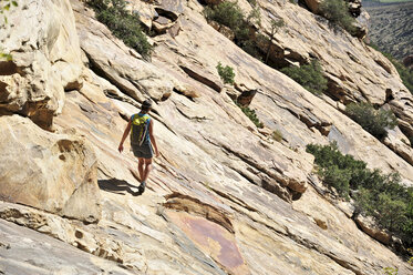 Young female rock climber crossing steep rockface, Mount Wilson, Nevada, USA - ISF11722