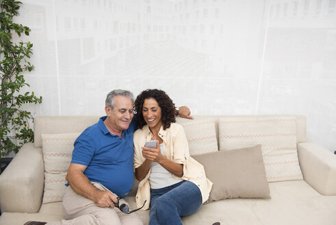 Älterer Mann und Frau lesen Smartphone-Texte auf dem Terrassensofa - ISF11781