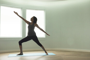 Reife Frau, die Yoga-Krieger-Pose in gebogenen Raum - ISF11785