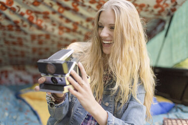 Junge Frau beim Fotografieren mit Sofortbildkamera beim Camping - ISF11810