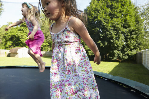 Zwei Mädchen springen auf einem Trampolin im Garten - ISF11838