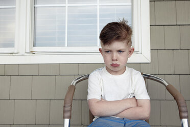 Porträt eines Jungen, der vor dem Haus sitzt und schmollt - ISF11839