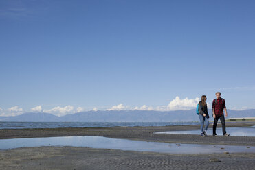 Young couple walking, looking at each other, Great Salt Lake, Utah, USA - ISF11867