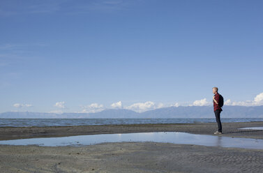Side view of young man standing at waters edge looking out, Great Salt lake, Utah, USA - ISF11868