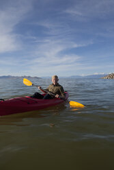 Young man in kayak holding paddles, looking at camera, Great Salt Lake, Utah, USA - ISF11877