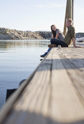 Side view of young couple sitting on wooden pier talking, Great Salt Lake, Utah, USA - ISF11881