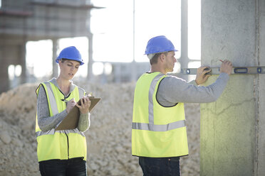 Builder using spirit level on construction site pillar - ISF11902