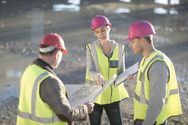 Architect and builders pointing to blueprint on construction site - ISF11904