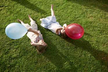 High angle view of brother and sister lying on grass holding balloon - ISF11931