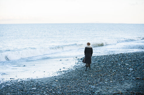 Rückansicht einer Frau, die am Strand spazieren geht - ISF11940