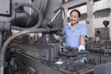 Female factory worker working on machine in crane factory, China - ISF12087