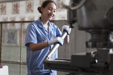 Weibliche Fabrikarbeiterin drückt den Maschinenhebel in einer Kranfabrik, China - ISF12088