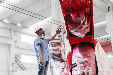 Männlicher Fabrikarbeiter, der einen roten Kran in einer Fabrik besprüht, China - ISF12091