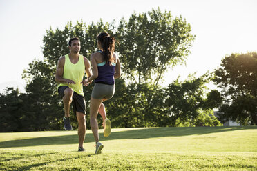 Young man and woman doing running on spot training in park - ISF12105