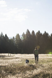 Vorderansicht einer mittleren erwachsenen Frau, die mit ihrem Hund spazieren geht und lächelnd nach unten schaut, Missoula, Montana, USA - ISF12119