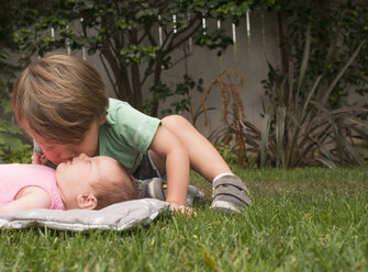 Junger Junge, der seine kleine Schwester küsst, im Freien - ISF12143