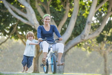 Mutter sitzt auf dem Fahrrad des Sohnes, der Sohn schiebt sie an - ISF12168