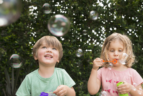 Young girl and boy blowing bubbles, outdoors - ISF12183