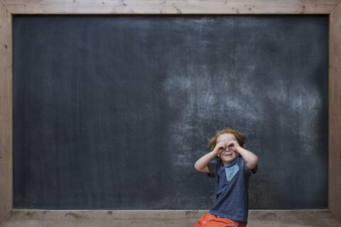 Junge vor einer Tafel stehend, der mit den Händen Gläser herstellt, lizenzfreies Stockfoto